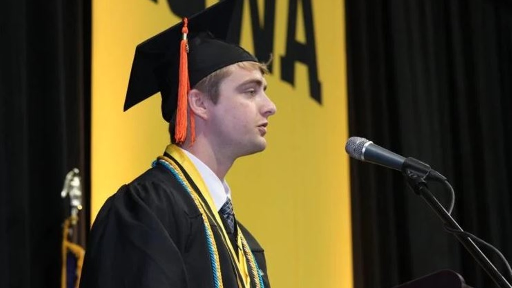 A person wearing a cap and gown speaking into a microphone