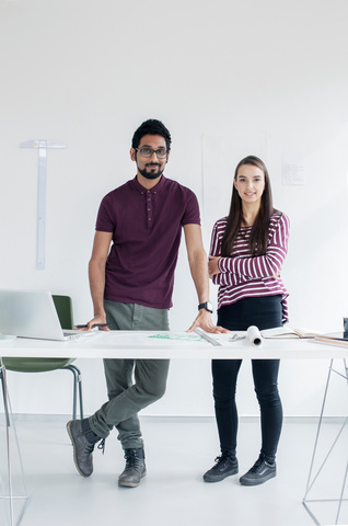 Two students standing by a desk