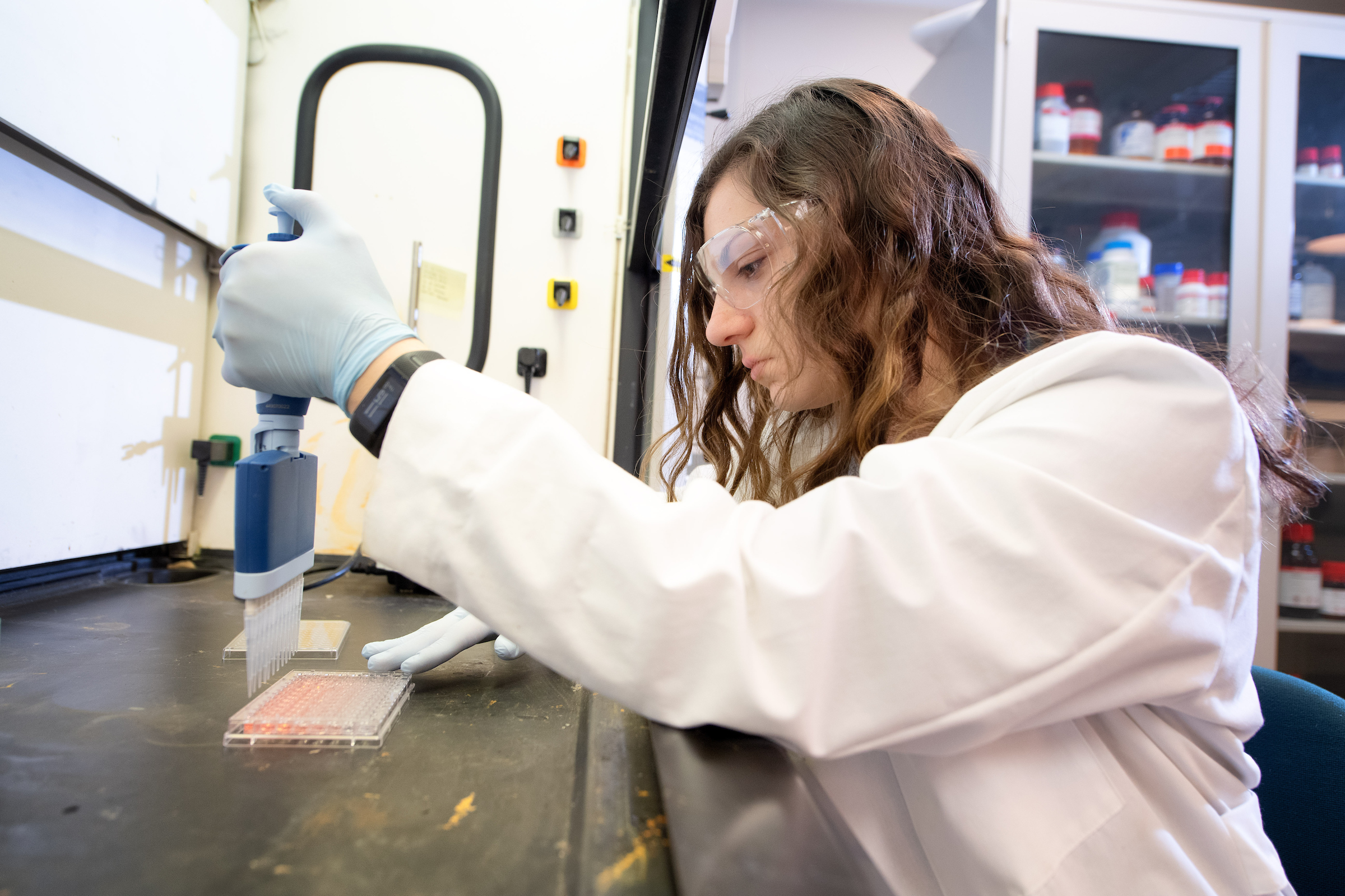 CBE student working in a lab, wearing goggles and a lab coat