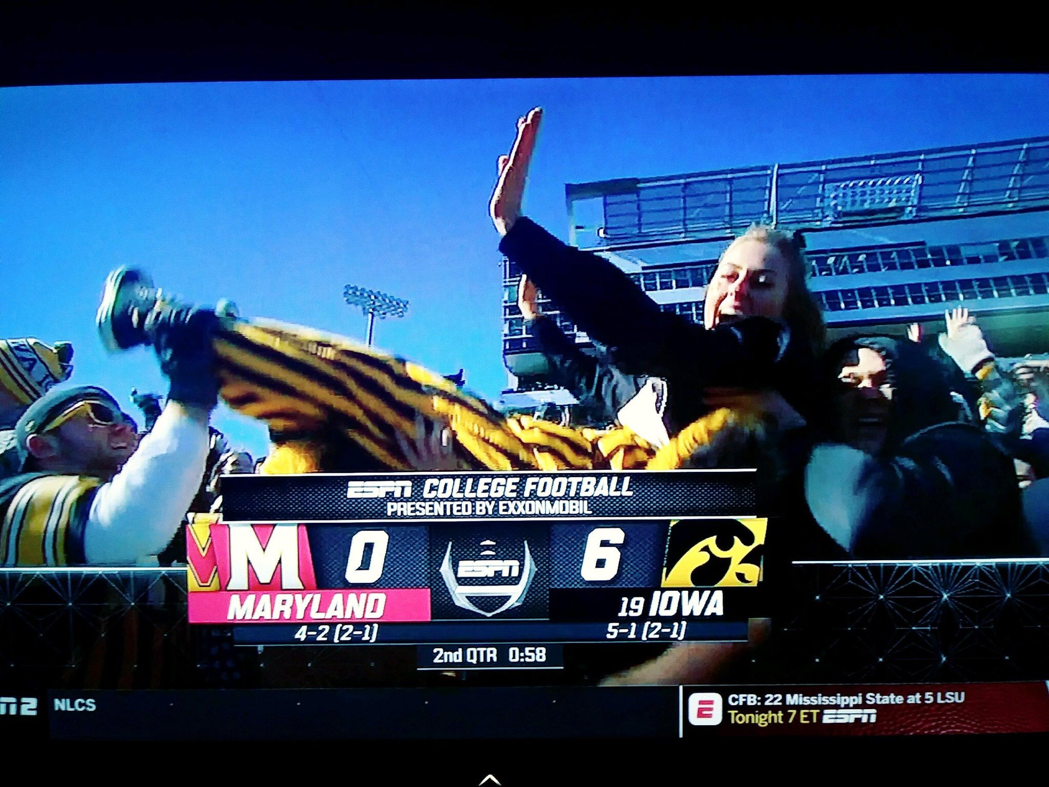Screencapture from TV broadcast of a crowd at a stadium pressing a woman in the air
