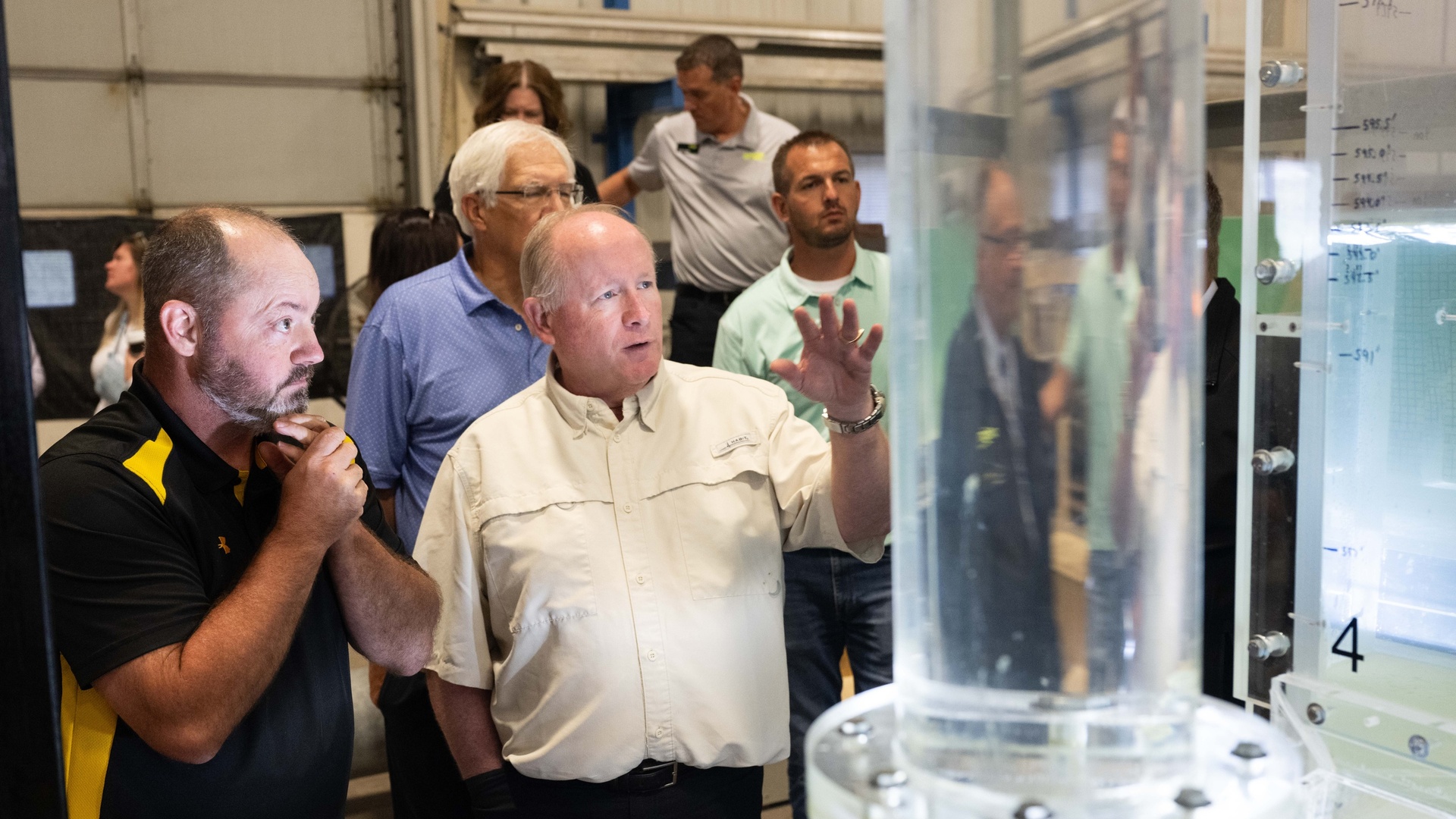 Tony Loeser (pictured, far left), an IIHR engineer, takes a question while meeting with community leaders from Dubuque, Iowa, standing next to clear water tubes.