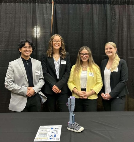 Four students standing behind the prosthetic leg they invented
