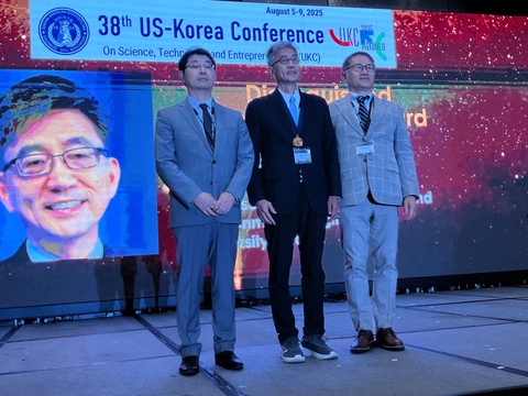 Lee poses with his award with a man on each side