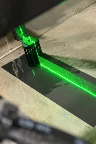 Green laser beam over dark surface