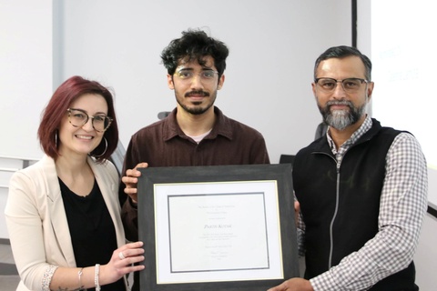 Three people pose with a framed certificate.