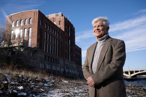 Researcher standing near a riverfront building on a clear winter day.