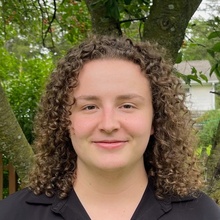 Student poses for a portrait with tree in background