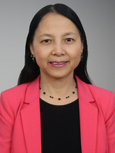 Portrait, woman with long dark hair, pink coat over black shirt. 
