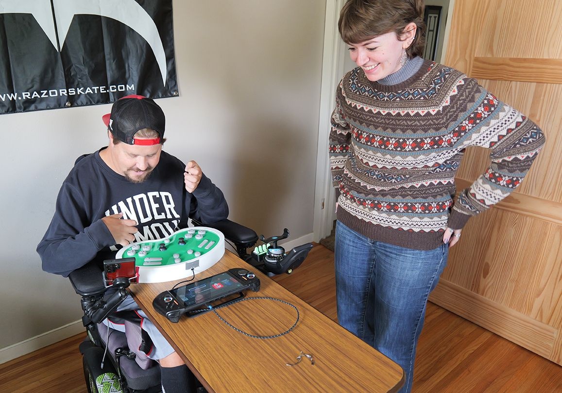 Biomedical engineering student Hope Mickey (right) presents the custom controller to Dylan Huntbach at his home in Waterloo.