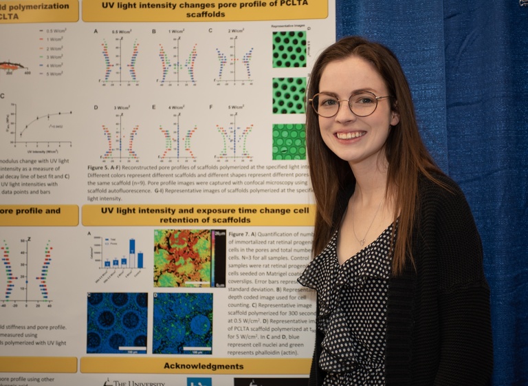 female student smiling in front of her research poster