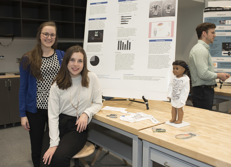 2 students posing in front of research poster