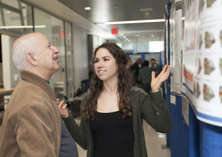 female student and man discussing contents of research poster