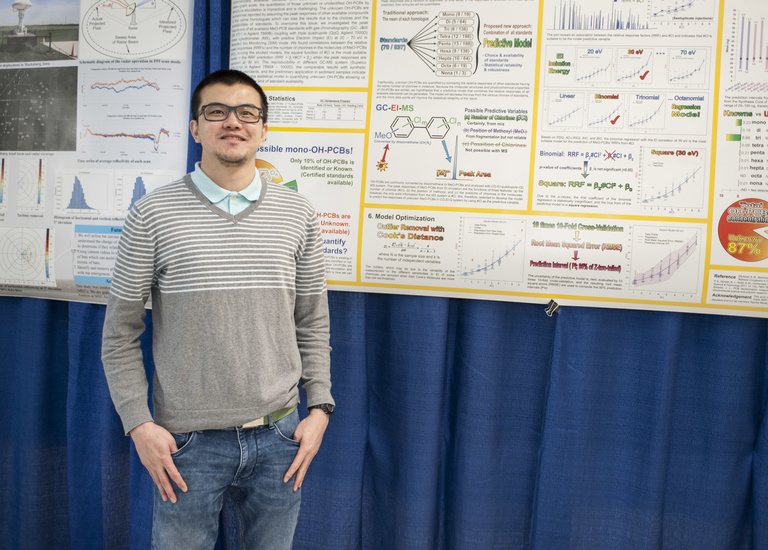 student posing in front of research poster