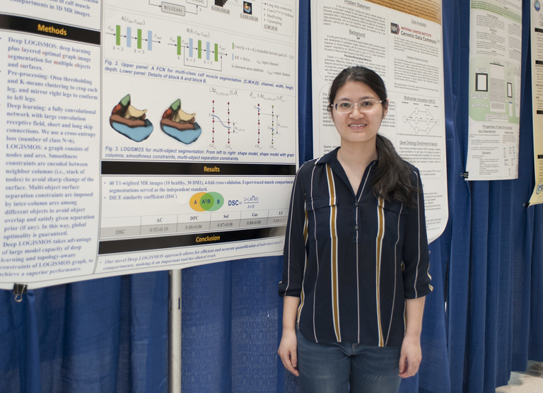 student smiling in front of row of research posters