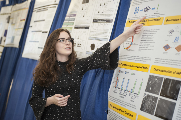 female student pointing at research poster