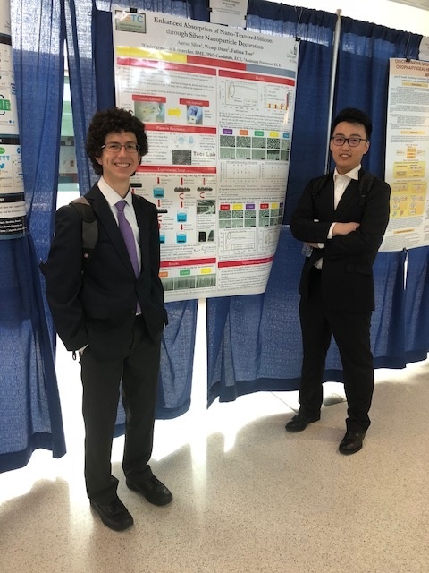 two students posing in front of a research poster