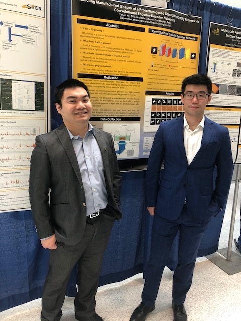 two students posting in front of the research poster 