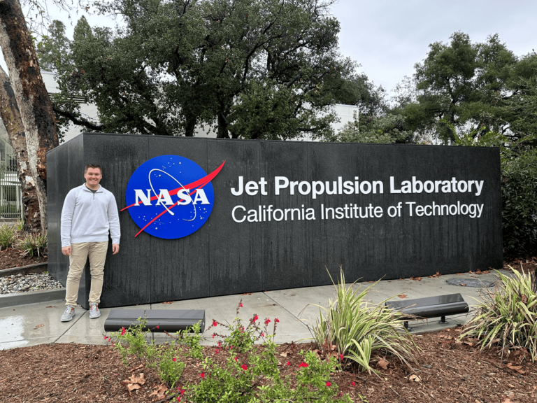Matt McDonnell stands next to a sign for the NASA Jet Propulsion Laboratory