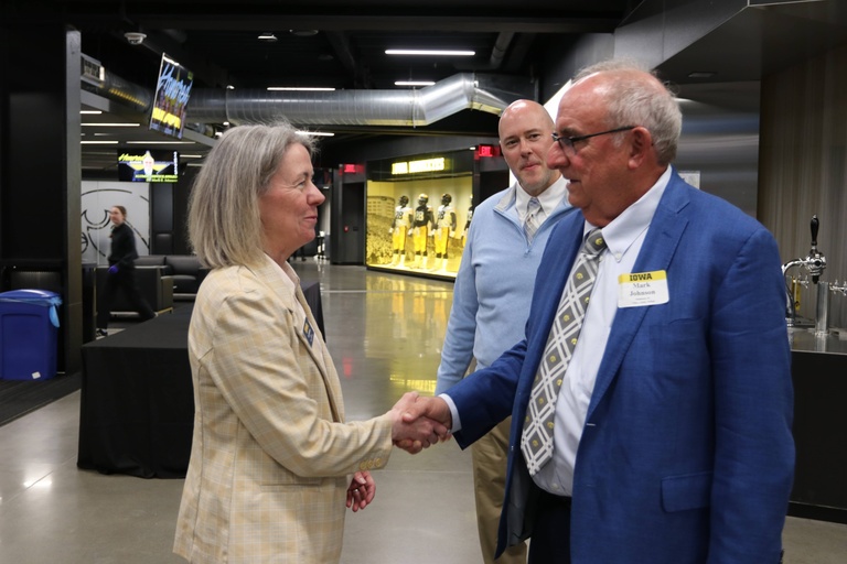 Ann McKenna (left) greets Mark Johnson while Michael Farrell looks on during an awards banquet for engineering alumni at Kinnick Stadium.