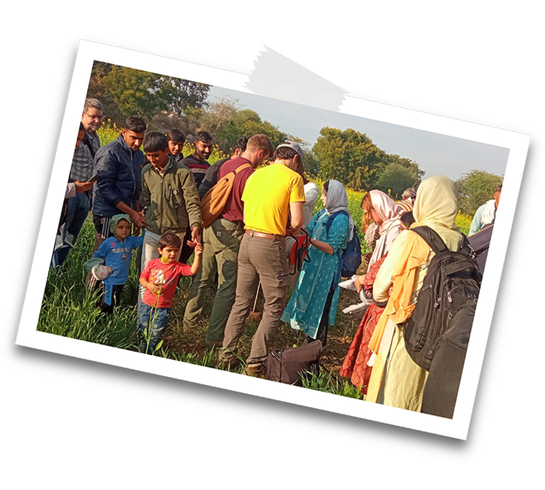 engineering students talk to locals in a grassy field