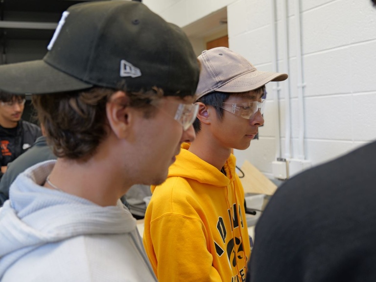 Side view of two students wearing caps and safety goggles.