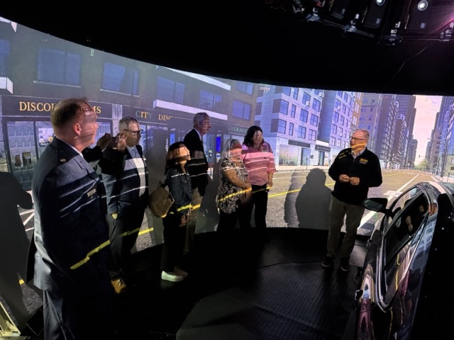 Group of people stand next to car with digital images in the background
