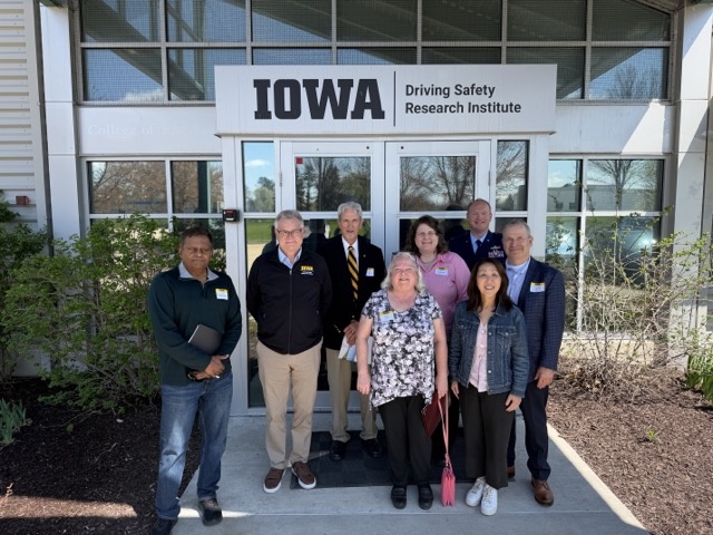 People pose for photo outside in front of sign "Iowa Driving Safety Research Institute"