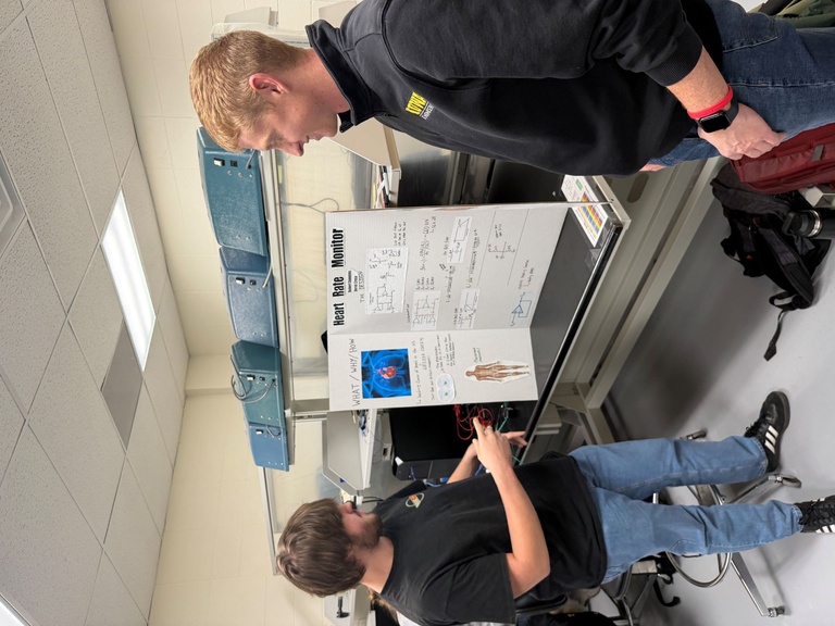 Man in navy shirt works on circuit at lab bench