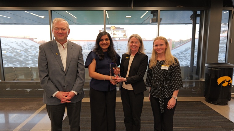 Woman (second from left) holds trophy with three people by her side