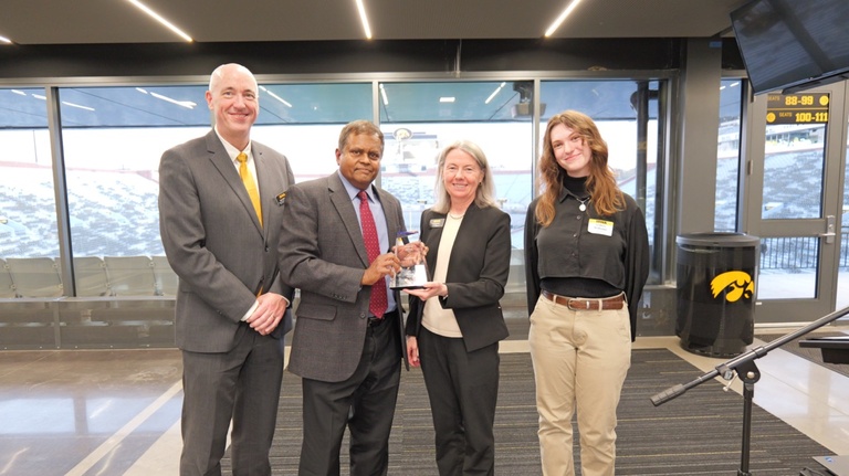 Man (second from left) holds trophy with three people by his side