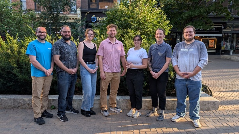 Group of graduate students standing together outdoors in a pedestrian mall.
