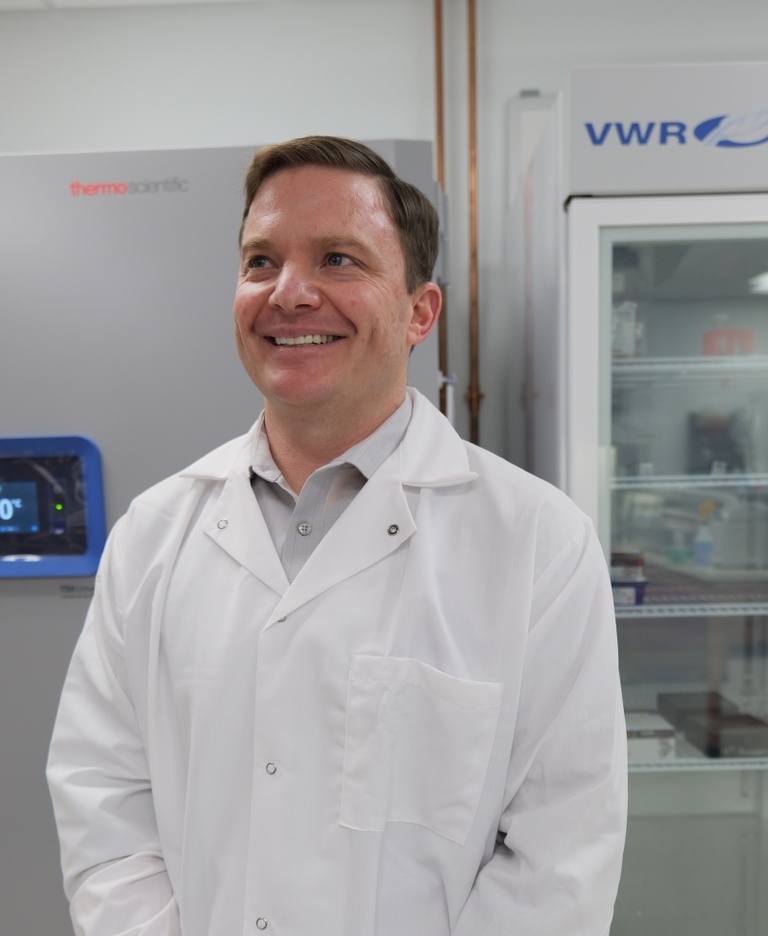 Patrick Link stands in his lab in a white coat