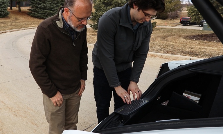 Chris Schwarz and Christopher Rundus work on the back of an electric vehicle