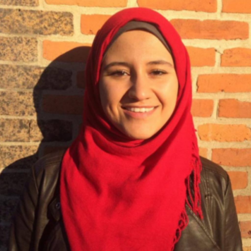 Student Mariam El- Hattab. She is smiling in a front of a red brick wall