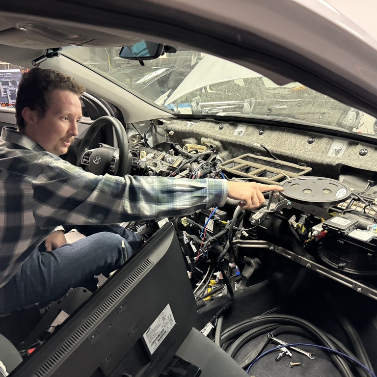 Reichert sits in the half-cab and points to the deconstructed dashboard of the vehicle