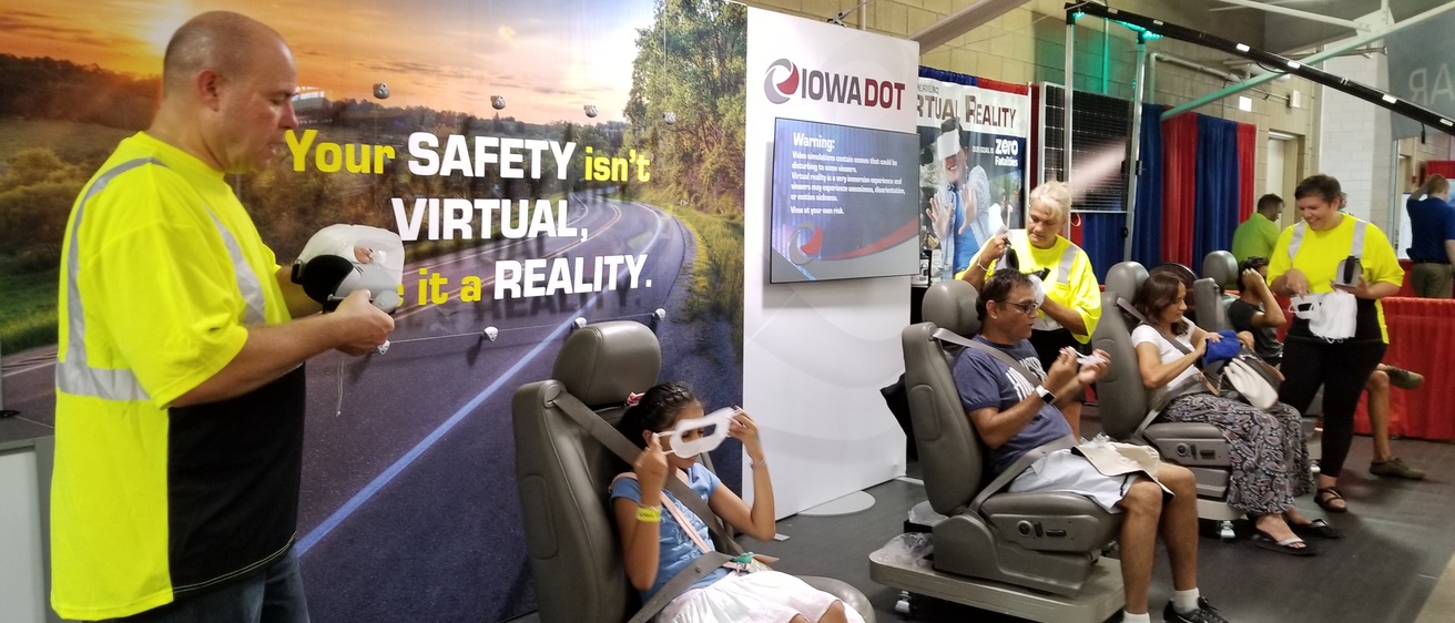 People sitting in car seats as part of virtual reality simulation at Iowa state fair