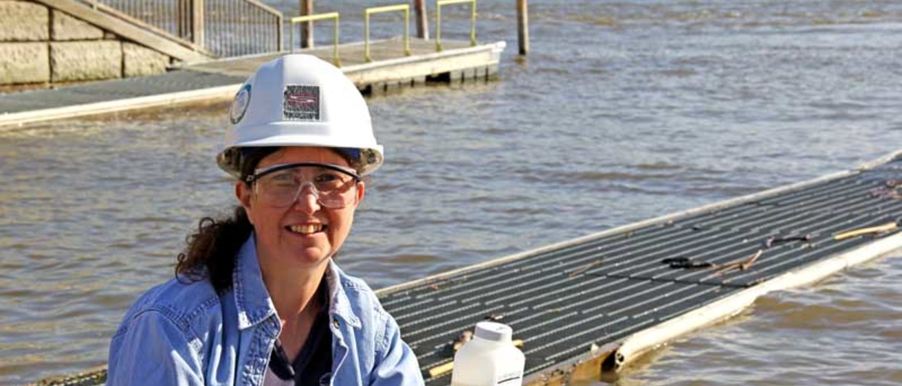Becky Svatos wearing a hard hat in front of a body of water