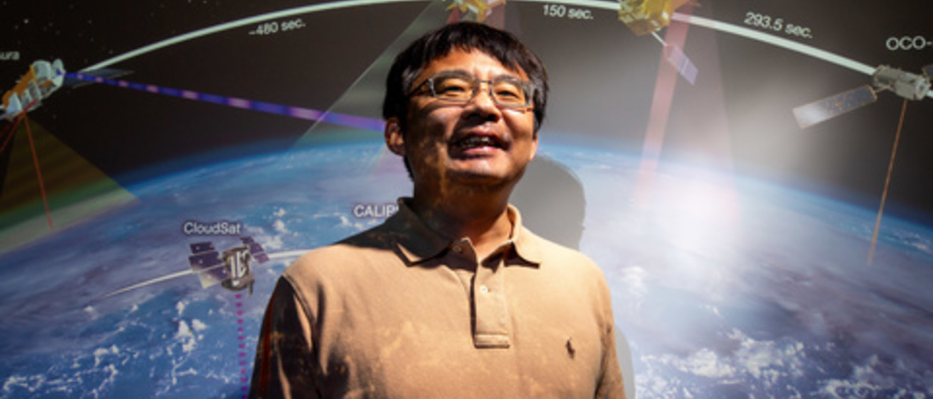 jun wang standing in front of a large image of the planet earth 