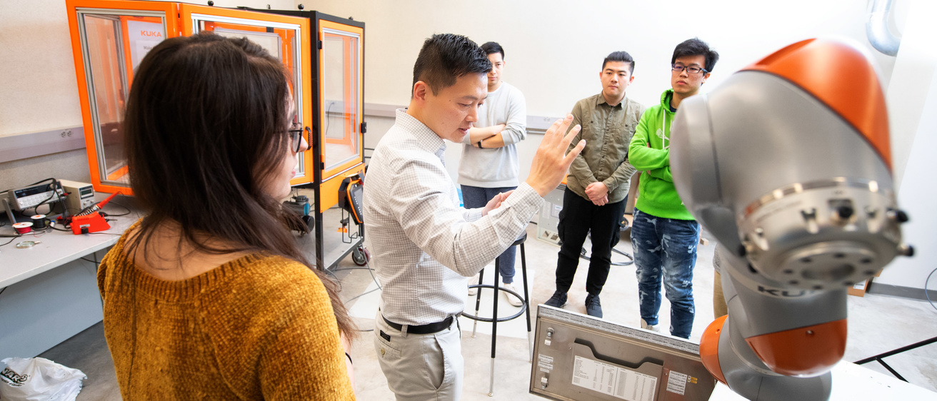 professor xiao works with students on kuka robot