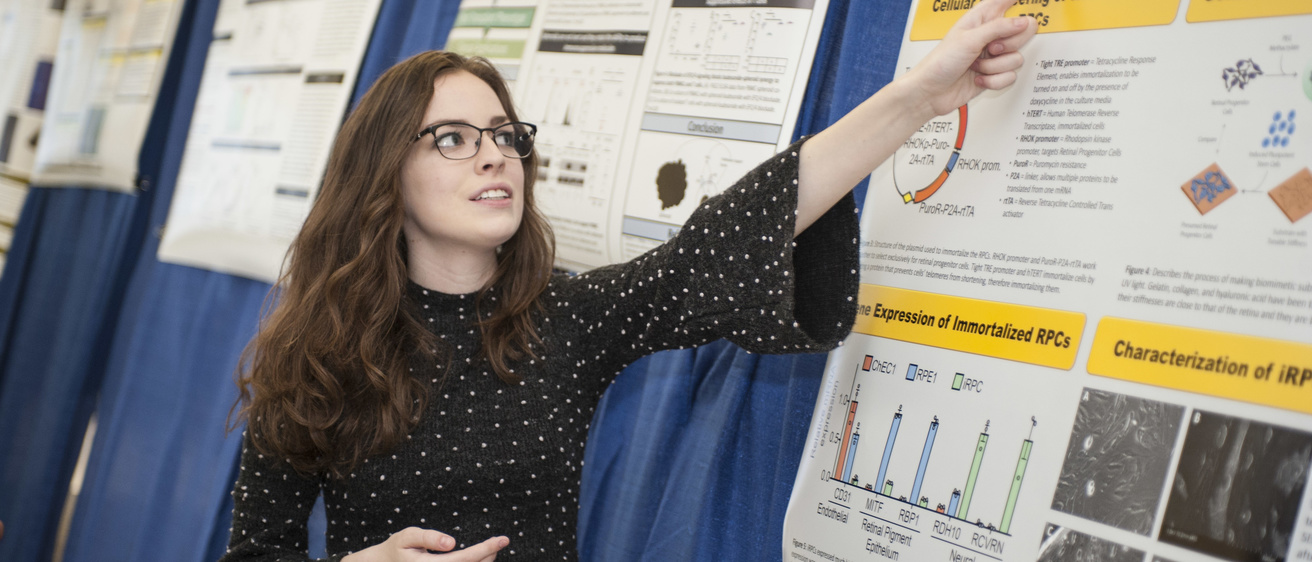 female student pointing at research poster