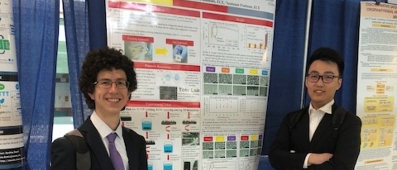 Two students posing in front of a research poster