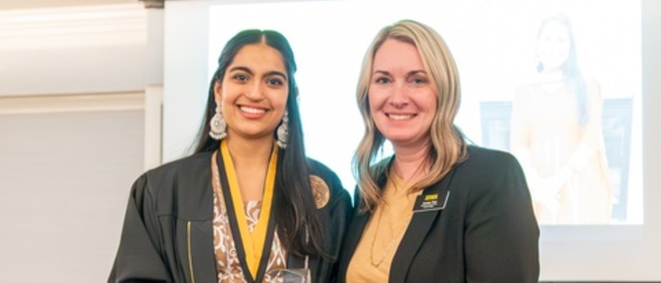 Bhavya holds award wearing graduation gown