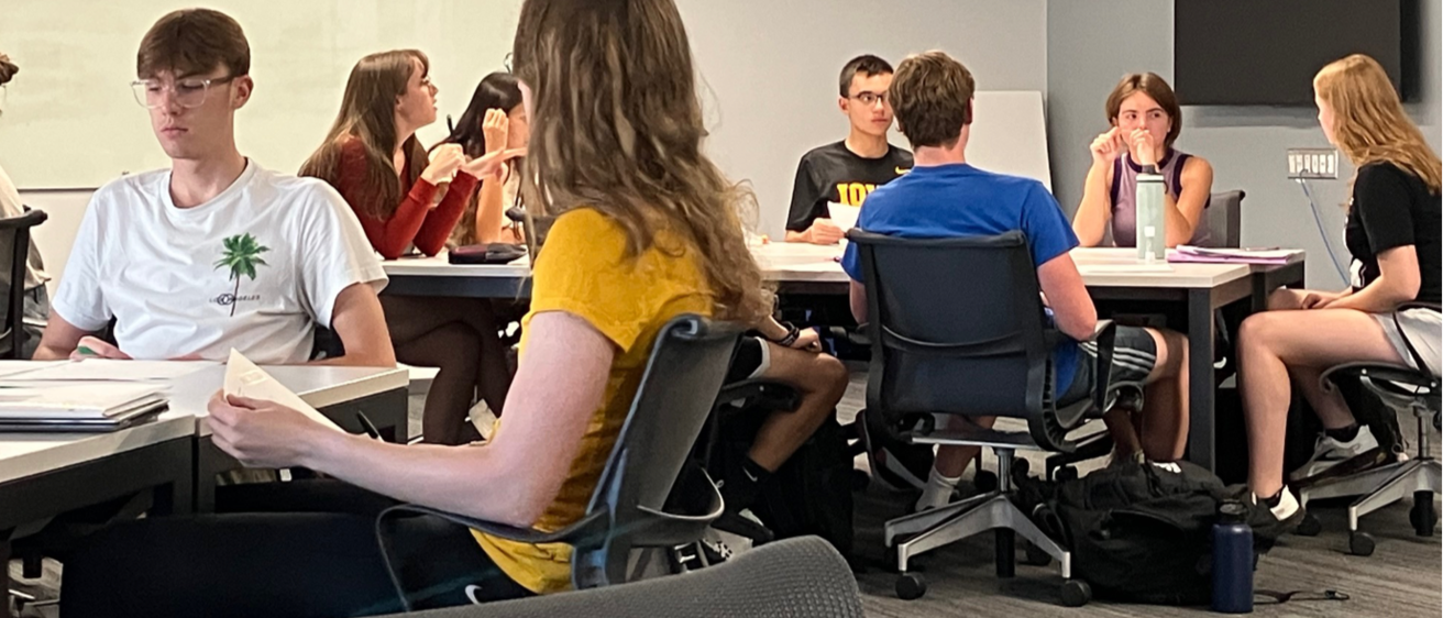 group of students sitting at tables talking to eachother