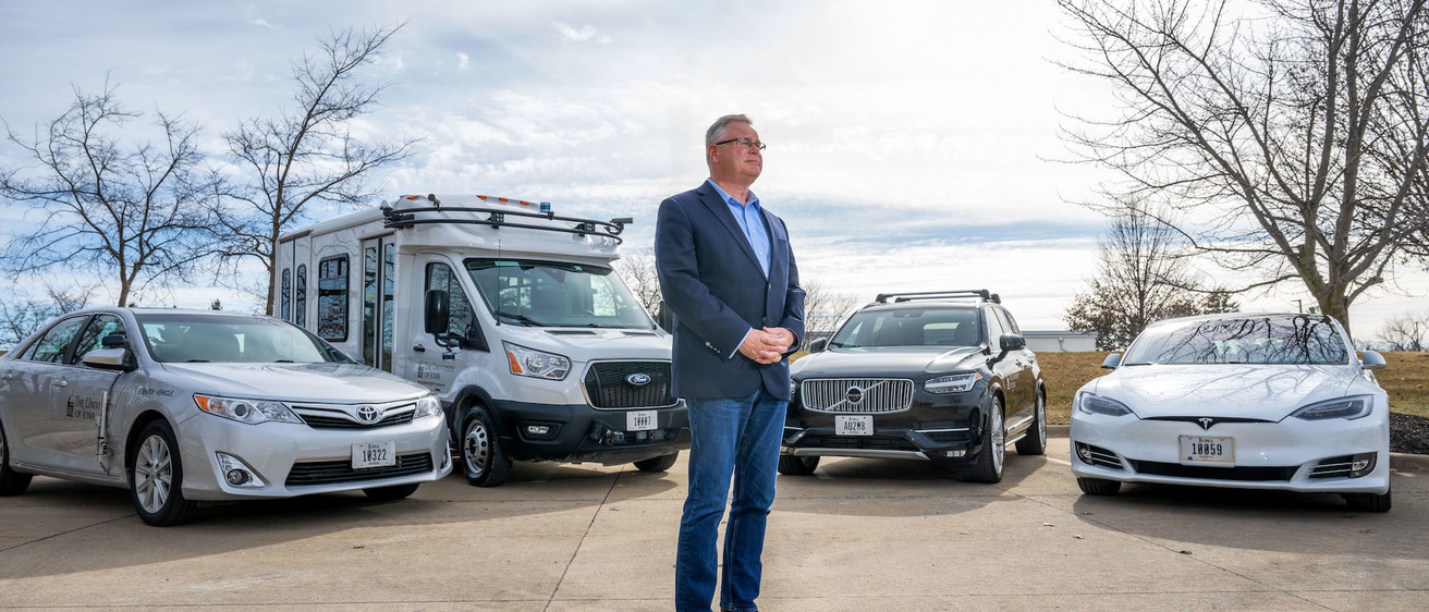Dan McGehee stands in front of four research vehicles