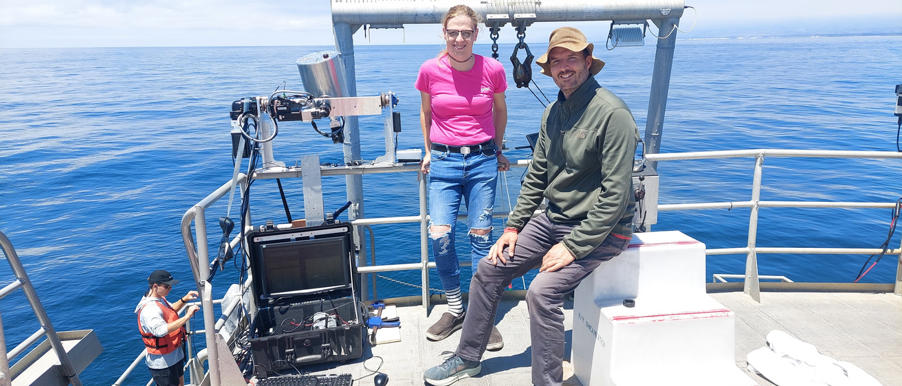 Two people stand on boat out in the ocean