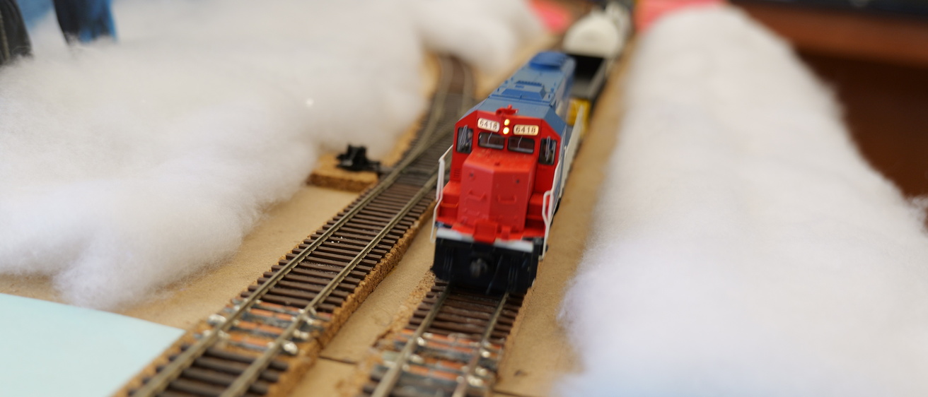 Model train on tracks approaches foreground