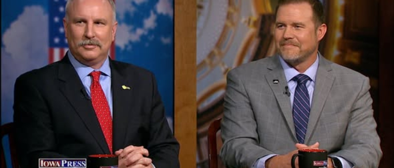 Television screenshot with "Iowa Press" in lower left corner, two men in suits with hands folded at table with coffee cups