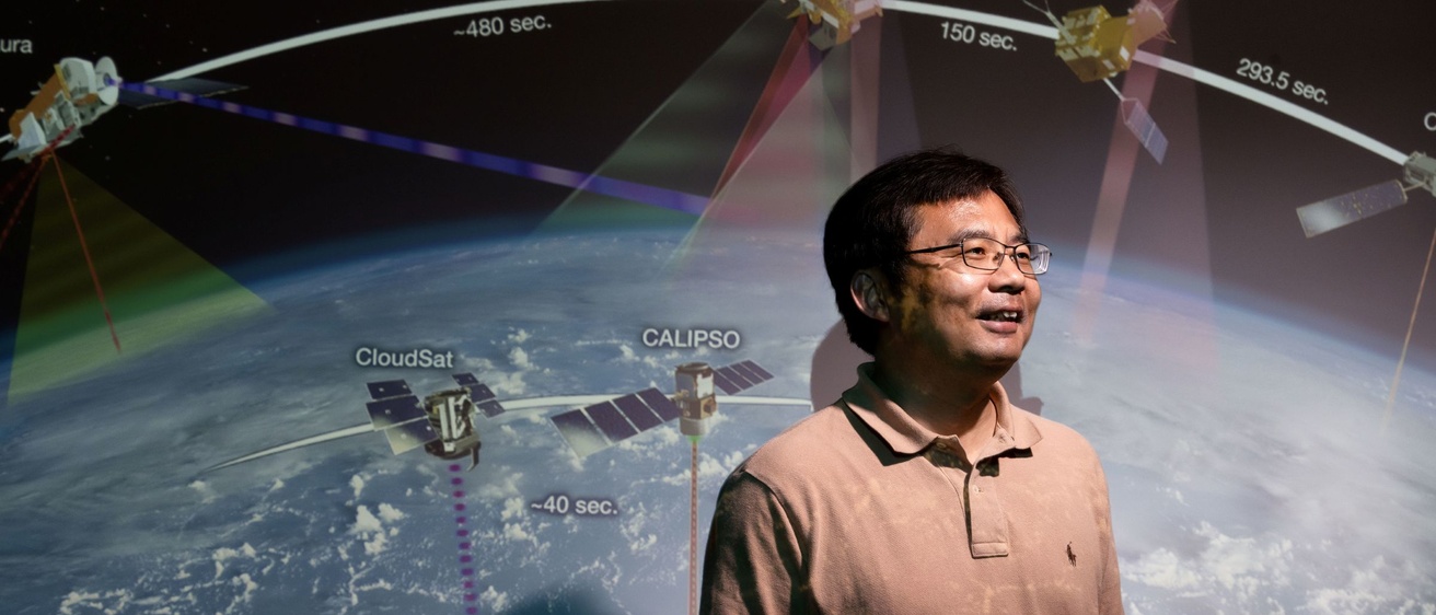 Professor stands in front of space and satellite image 