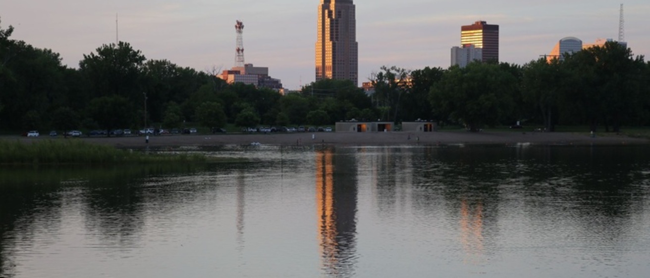 Kayaker in body of water with Des Moines skyline in background