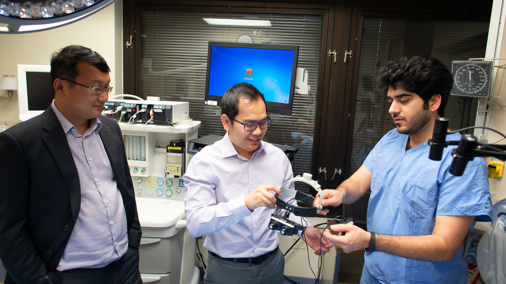 Three people looking at CCAD smart goggles in a hospital room
